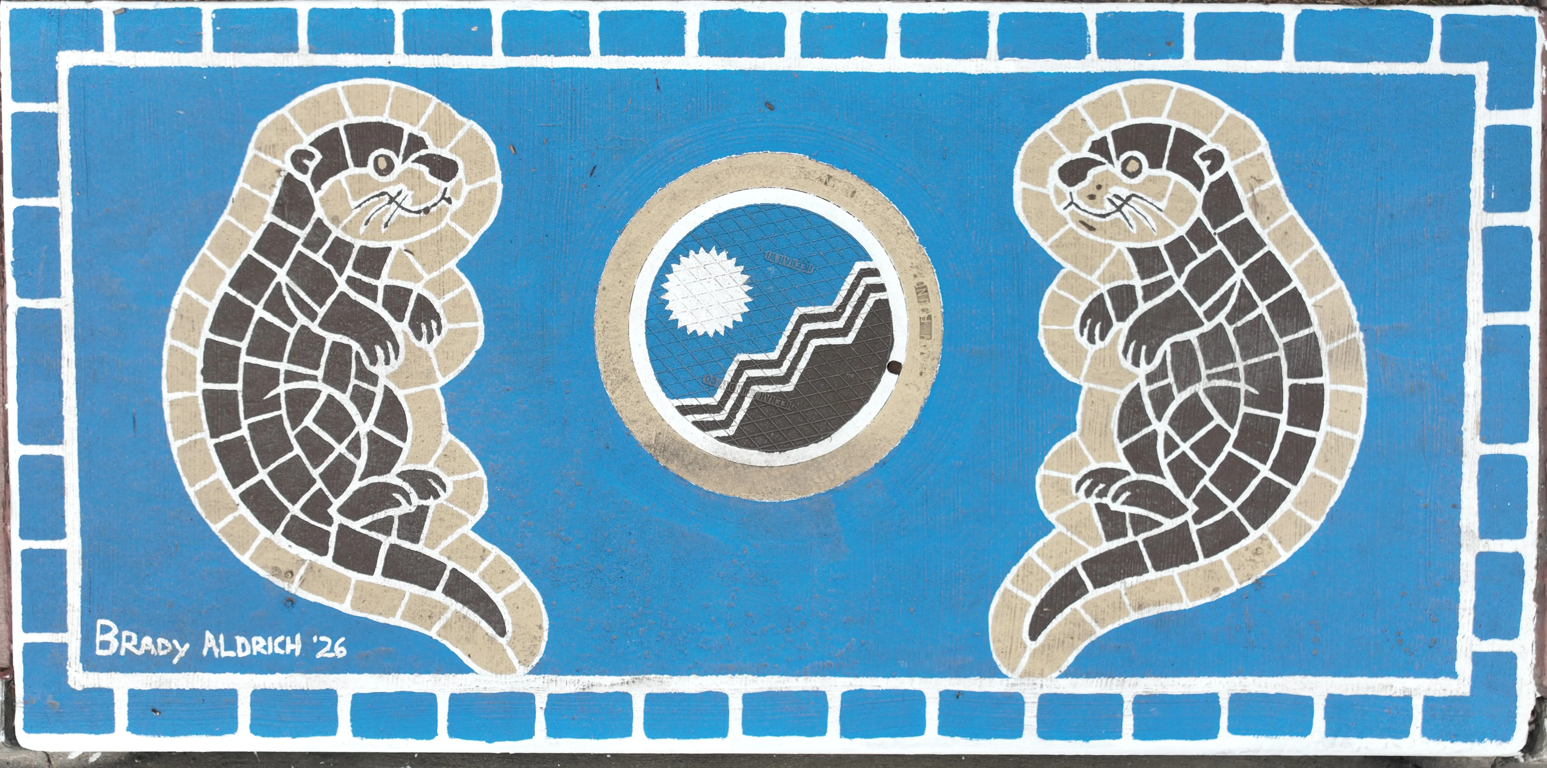 A storm drain mural featuring two otters facing on either side facing inwards towards a City of Sioux Falls design on the manhole cover, with a blue background.