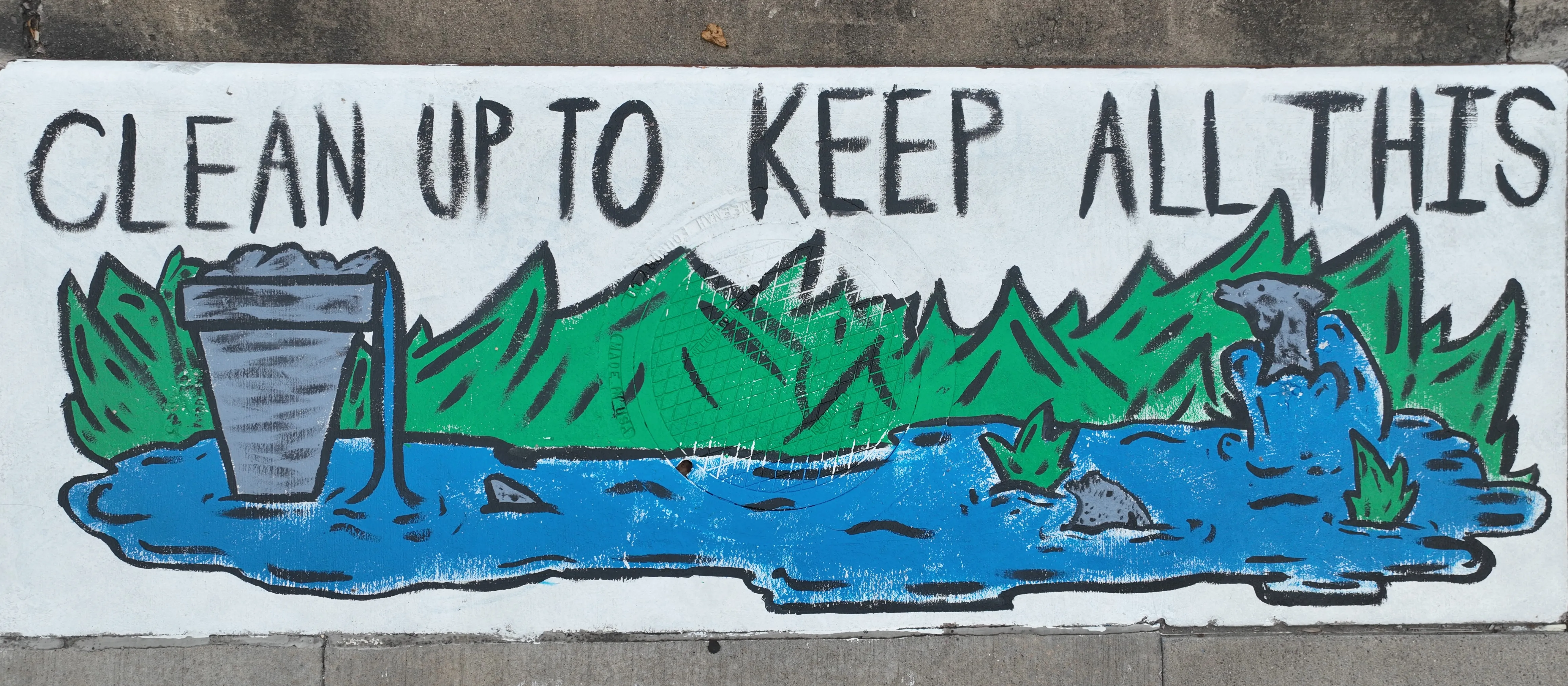 A mural on a storm inlet drain featuring a lake and green background. A large trash can in the left of the lake is spilling water into the lake. Fish are poking and jumping out of the water. Text reads "Clean up to keep all this"