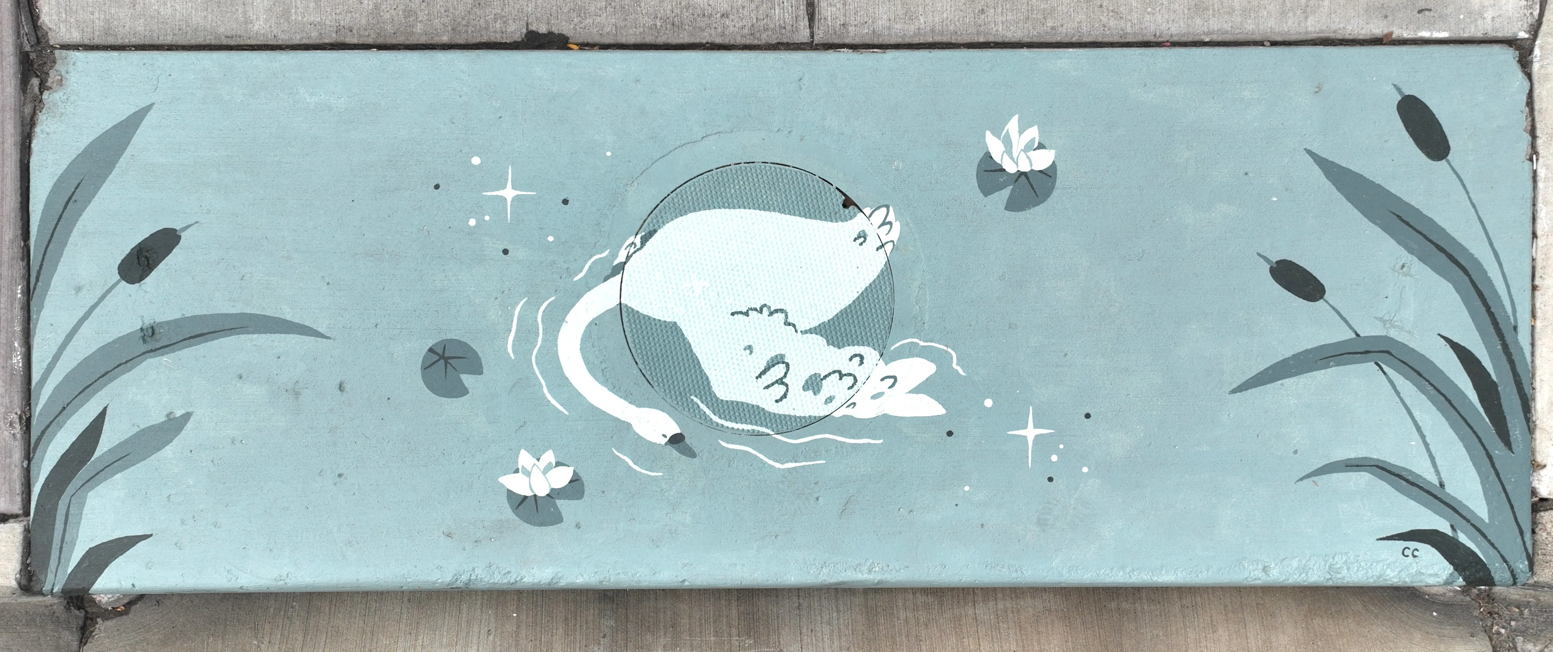 A mural on a storm inlet depicting a top-down viwee of a swan in a body of water, surrounded by lily pads and other shapes.