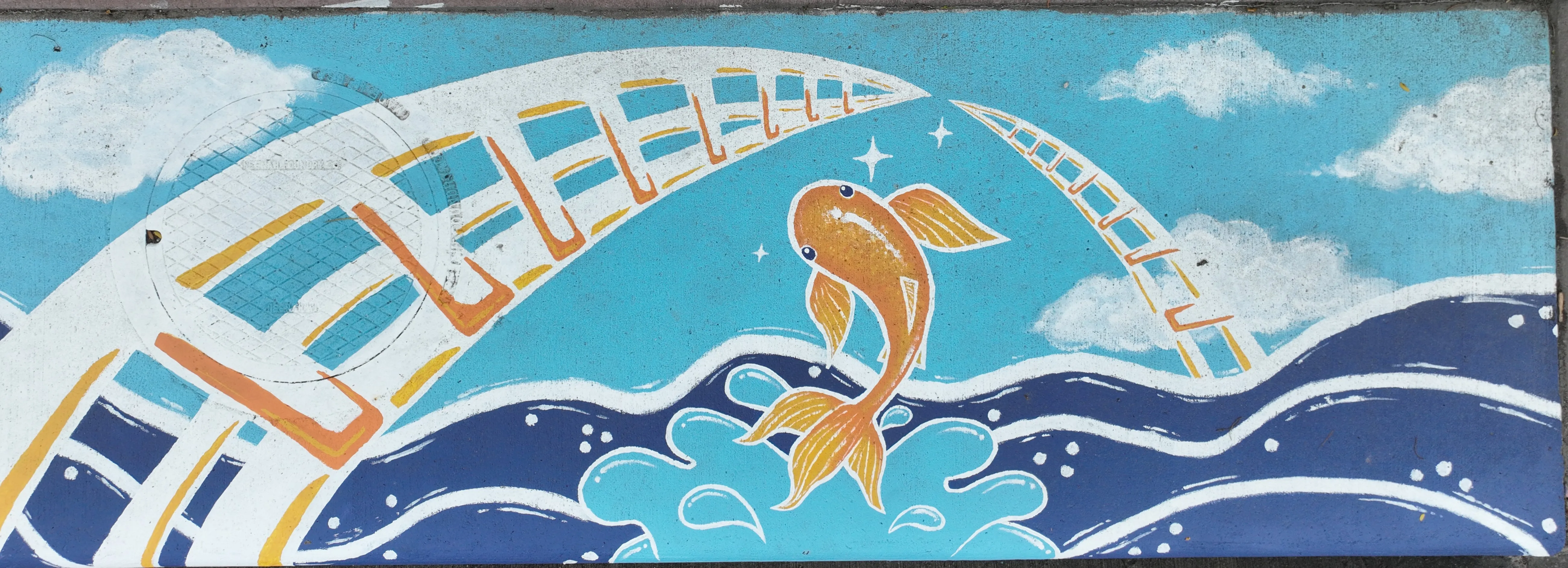 A mural on a stormwater inlet showing a brigh orange fish jumping from a river interserected by an arch sculpture.