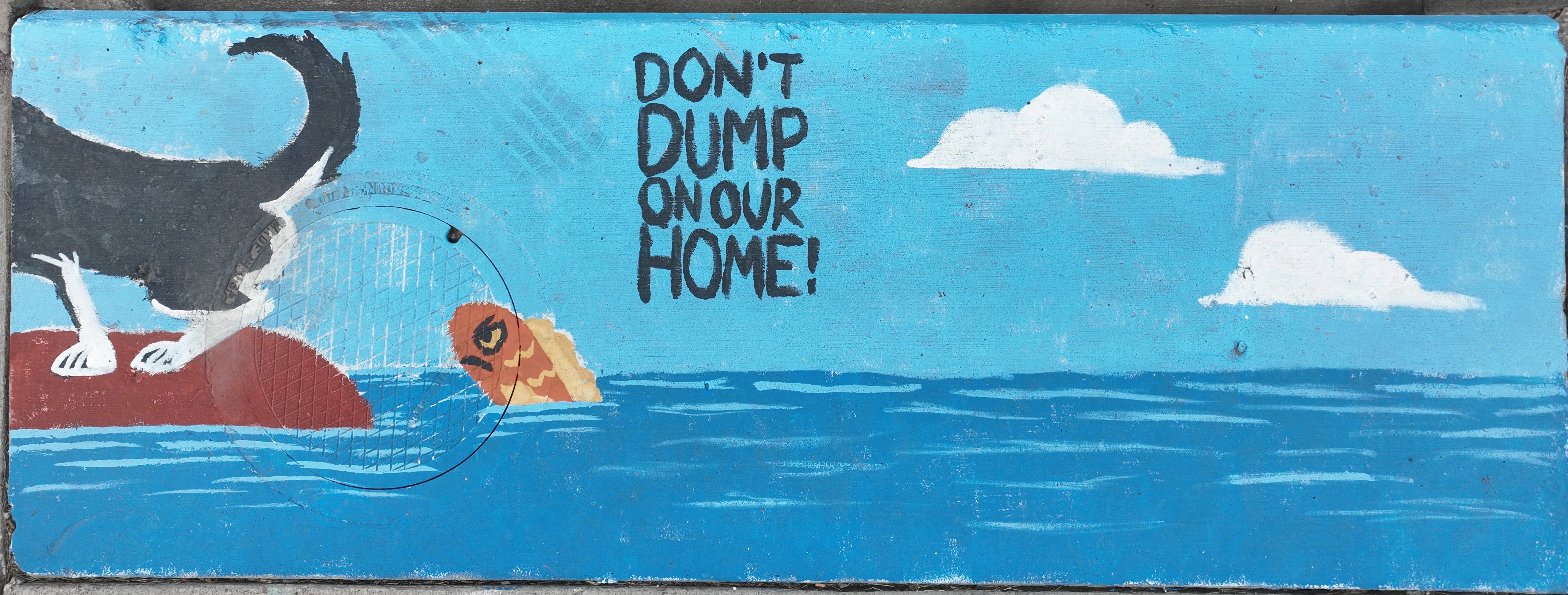 A mural on a stormwater inlet depicting a dog with its rear end pointed into a body of water, with a fish looking angrily upwards. Text reads "Don't dump on our home"